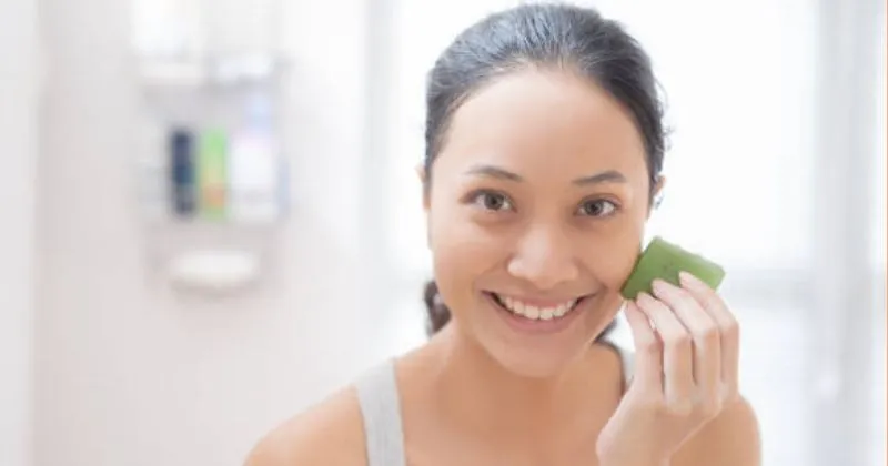 A young female with a piece of aloe vera in her hand